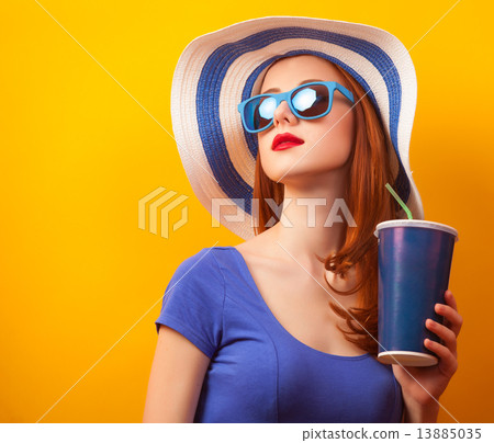 Redhead girl with drink and sunglasses on yellow background 13885035