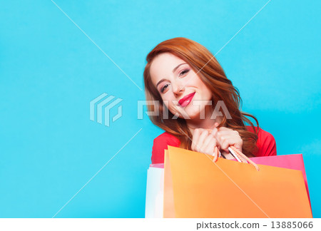 Redhead girl with shopping bags on blue background. 13885066