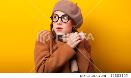 Redhead girl in coat and scarf on yellow background. Redhead girl in coat and scarf on yellow background. 13885105