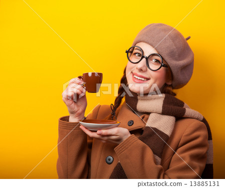 Redhead girl with coffee on yellow background 13885131