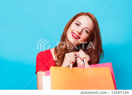 Redhead girl with shopping bags on blue background. Redhead girl with shopping bags on blue background. 13885184