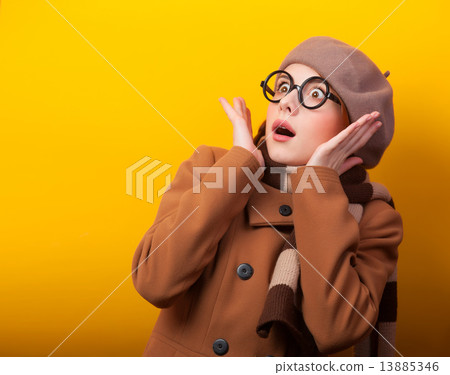 Redhead girl in coat and scarf on yellow background. Redhead girl in coat and scarf on yellow background. 13885346