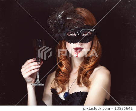 Redhead vampire woman in mask with glass of blood. Redhead vampire woman in mask with glass of blood. 13885641