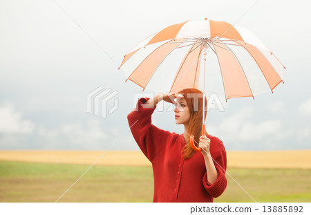 Redhead girl with umbrella at meadow Redhead girl with umbrella at meadow 13885892