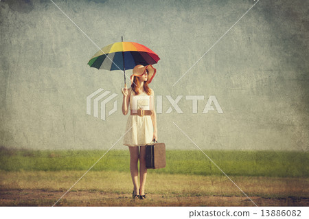 Redhead enchantress with umbrella and suitcase at spring country 13886082
