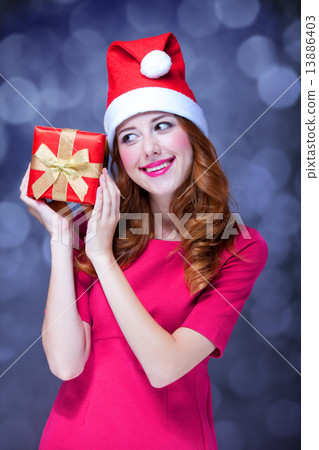 Redhead girl in christmas hat with gift. 13886403
