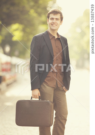 Man with suitcase walking outdoors Man with suitcase walking outdoors 13887439