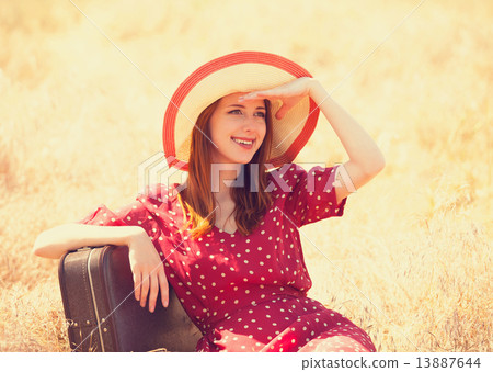 Redhead girl with suitcase sitting at grass Redhead girl with suitcase sitting at grass 13887644