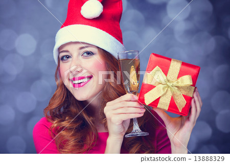 Redhead girl in christmas hat with gift and champagne 13888329