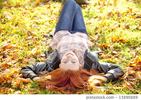 Happy red-haired girl at the park in autumn. 13890889