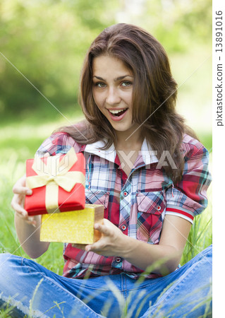 Beautiful teen girl with gift in the park at green grass. Beautiful teen girl with gift in the park at green grass. 13891016