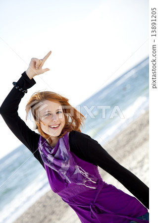 Portrait of red-haired girl with headphone on the beach. 13891205