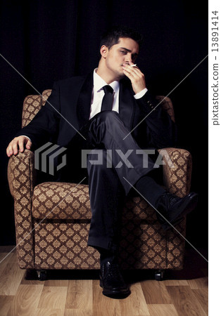 Man with cigarette sitting in vintage armchair 13891414