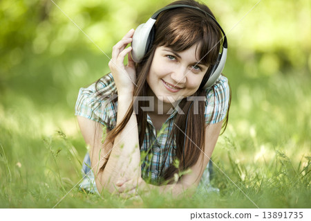 Young fashion girl with headphones at green spring grass. 13891735
