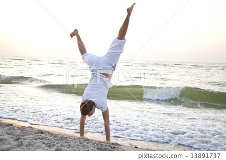 Young man doing cartwheels on the beach 13891737