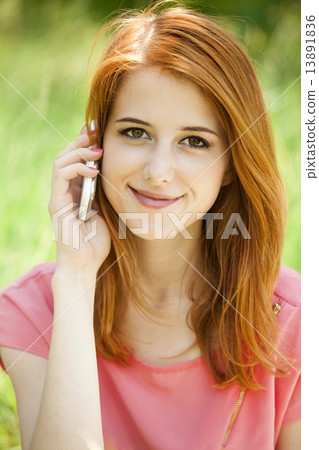 Redhead girl with mobile phone at the park. 13891836