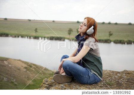 Young fashion girl with headphones at rock near lake. 13891992