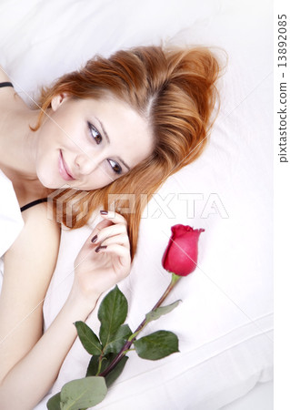 Beautiful red-haired girl with rose in the bedroom. 13892085