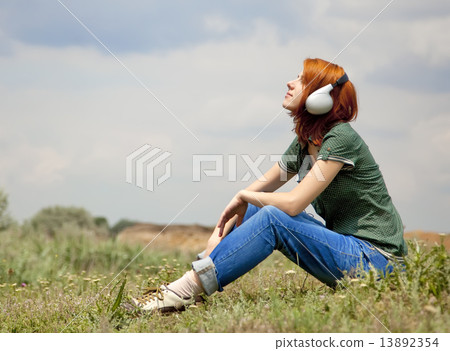 Young fashion girl with headphones at grass in spring time. 13892354