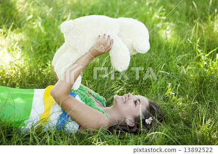 Beautiful teen girl with Teddy bear in the park at green grass. Beautiful teen girl with Teddy bear in the park at green grass. 13892522