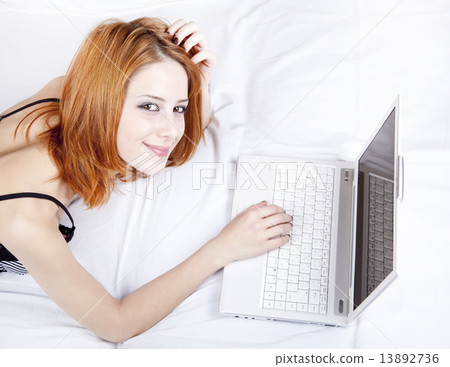 Beautiful red-haired girl with notebook in the bed. Beautiful red-haired girl with notebook in the bed. 13892736