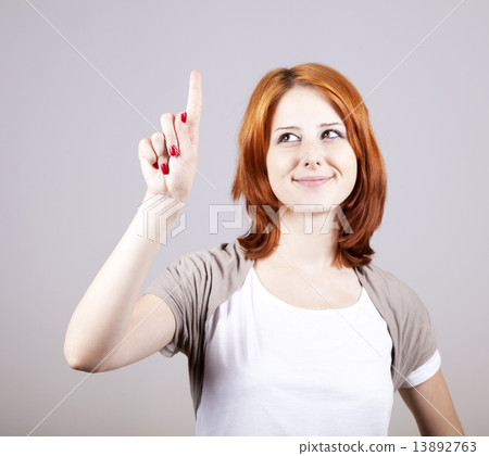 Red-haired businesswoman show her finger on something in air. Red-haired businesswoman show her finger on something in air. 13892763