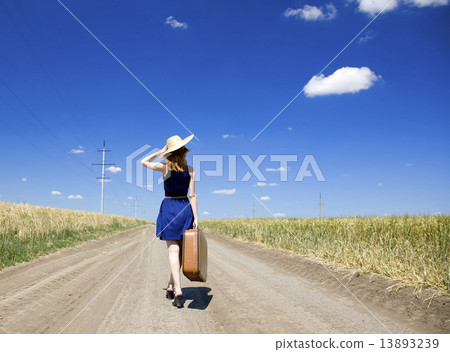 Lonely girl with suitcase at country road. 13893239