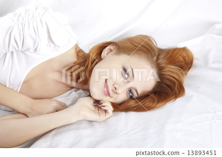 Pretty red-haired sleeping woman in white nightie lying in the b 13893451
