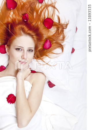 Beautiful red-haired girl in bed with rose petal. 13893535