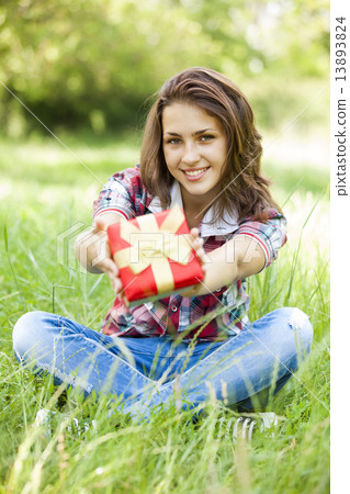 Beautiful teen girl with gift in the park at green grass. 13893824