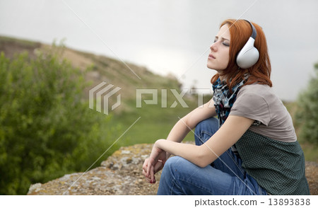 Young fashion girl with headphones at rock near lake. Young fashion girl with headphones at rock near lake. 13893838