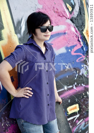 Style girl with skateboard near graffiti wall. 13893911