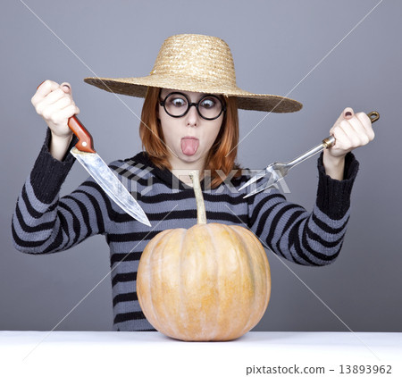 Funny girl in cap and fork with knife try to eat a pumpkin. 13893962