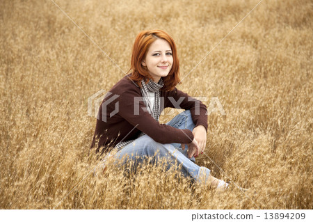 Beautiful red-haired girl at yellow autumn grass. 13894209