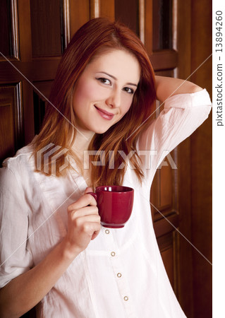 Style redhead girl drinking coffee near wood doors. Style redhead girl drinking coffee near wood doors. 13894260