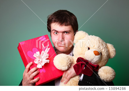 Boy with present box and teddy bear can't select a present in St 13894286
