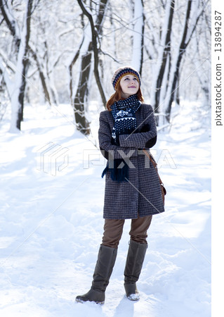 Beautiful young red-haired woman in winter park 13894287