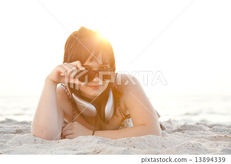 Beautiful brunette girl with headphones at beach sand. 13894339