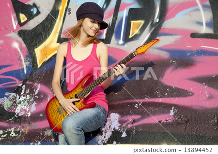 Beautiful red-haired girl with guitar and graffiti wall at backg Beautiful red-haired girl with guitar and graffiti wall at backg 13894452