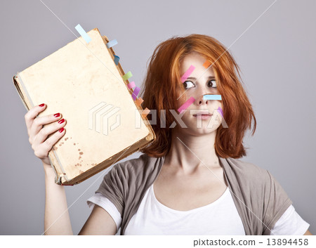 Red-haired businesswoman with book and notes on face. 13894458