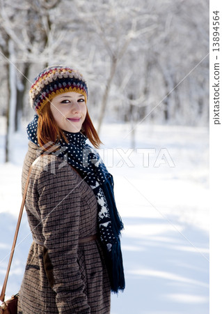 Beautiful young red-haired woman in winter park 13894564