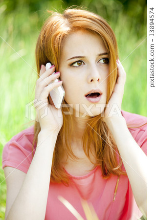 Angry redhead girl with mobile phone at the park. 13894574