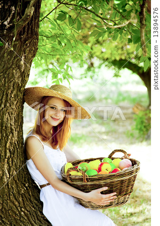 Beautiful redhead girl with fruits in basket at garden. 13894576