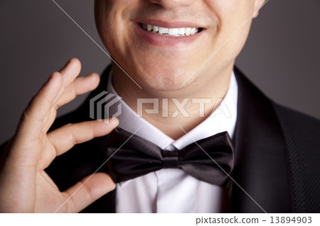 A close-up shot of a man straightening his tux. 13894903