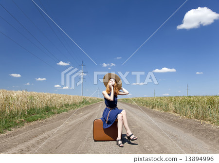 Lonely girl with suitcase at country road. 13894996