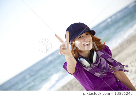 Red-haired girl with headphone on the beach. 13895243