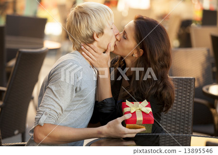The young man gives a gift to a young girl in the cafe and they 13895546