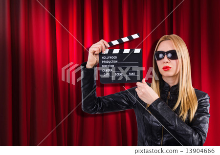 Girl with movie board against curtains 13904666