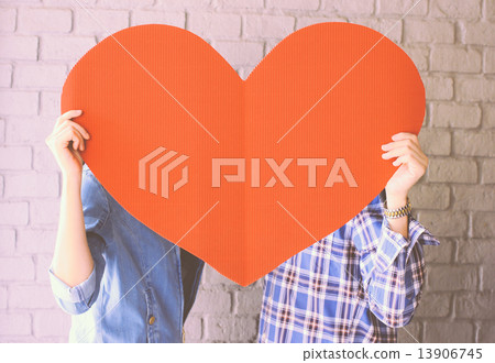 Couple holding handmade paper heart with retro filter effect Couple holding handmade paper heart with retro filter effect 13906745