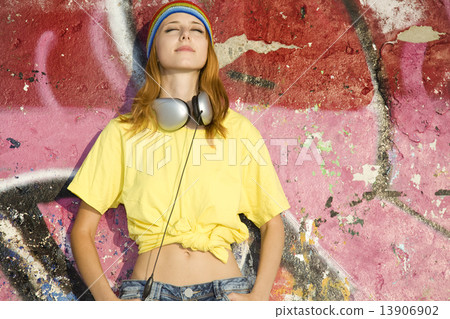 Beautiful girl with headphones and graffiti wall at background. 13906902